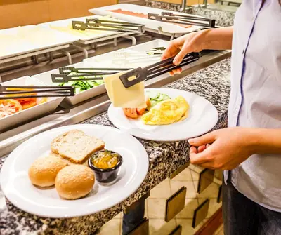 a person holding two plates of food on a counter at Baan Yuree Resort & Spa - SHA Plus in Patong Beach