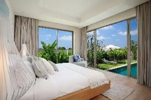 a bedroom with a white bed and a large window at Trichada Villas by RESAVA in Bang Tao Beach