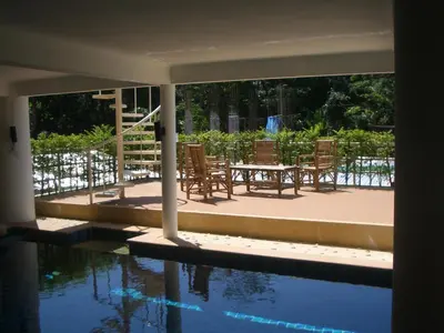 a patio with chairs and a table next to a pool at Surin villa in Surin Beach