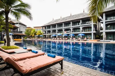 a swimming pool with two lounge chairs in front of a hotel at Ramada by Wyndham Aonang Krabi in Ao Nang Beach