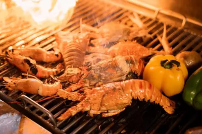 a grill with lobster and a tomato and peppers at Thavorn Palm Beach Resort Phuket in Karon Beach