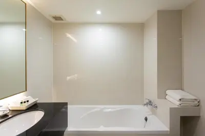 a white bathroom with a tub and a sink at Krabi Heritage Hotel in Ao Nang Beach