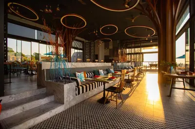 a restaurant with couches and tables and windows at The SIS Kata Resort - Adult Only in Kata Beach