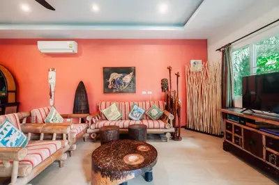 a living room with orange walls and couches and a tv at Chaba Pool Villa Private Tropical Villa With Pool in Nai Harn Beach