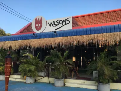 a restaurant with a straw roof and palm trees outside at Peaceful homestay in Rawai Beach