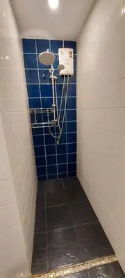 a shower in a bathroom with a blue tile wall at Cafe de Paris in Patong Beach