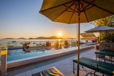 a pool with chairs and an umbrella and the ocean at Kantary Bay Hotel Phuket in Panwa Beach