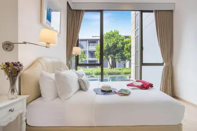 a bedroom with a white bed with a large window at Luxury Oceanfront_pool access apartment in Mai Khao Beach