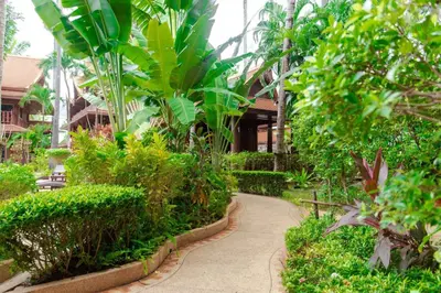 a walkway through a garden in front of a building at Royal Phawadee Village Patong - 2 Minutes walk to the beach in Patong Beach
