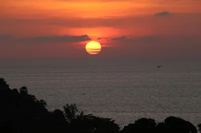 a sunset over the ocean with the sun in the sky at Sea and Sky Condominium Room #406 in Karon Beach