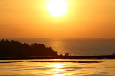 a sunset over the ocean from a swimming pool at Sea and Sky Condominium Room #406 in Karon Beach
