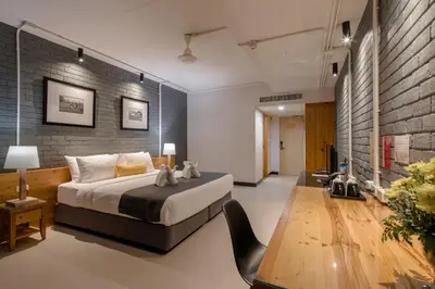 a bedroom with a large bed and a brick wall at DARA Hotel in Phuket Town