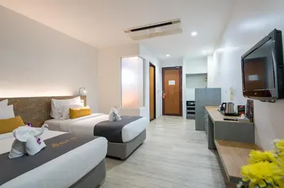 a hotel room with two beds and a flat screen tv at DARA Hotel in Phuket Town