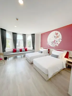 a bedroom with two beds and a pink wall at Hotel Midtown Ratsada in Phuket Town