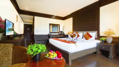 a bedroom with a bed and a living room with a table at Aonang Orchid Resort in Ao Nang Beach