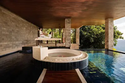 a woman is sitting on a bench in a pool at Paresa Resort Phuket in Kamala Beach