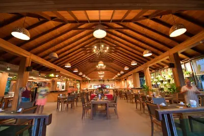 a restaurant with wooden ceilings and tables and chairs at Tup Kaek Sunset Beach Resort-SHA Plus in Tab Kaek Beach