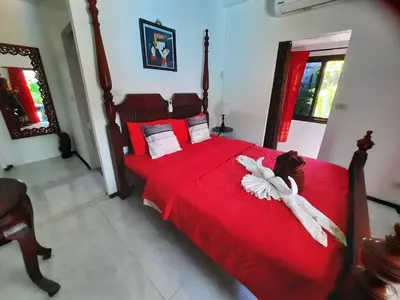 a bedroom with a large red bed with white sheets at Bjou, Cosy Tropical Villa in Rawai Beach