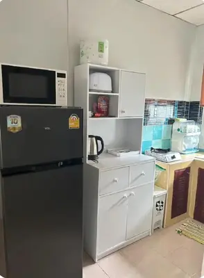 a kitchen with a black refrigerator and white cabinets at The Endless Bangtao Residence PM12 in Bang Tao Beach