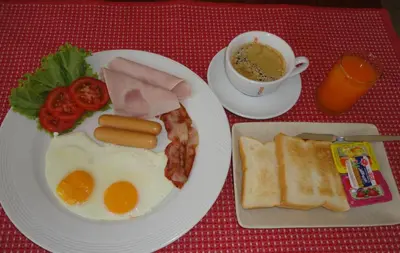 a plate of breakfast food with eggs bacon and a cup of coffee at Tony Home and Restaurant in Karon Beach