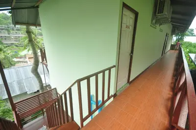 a balcony of a building with a door and a bench at Sand Sea House in Phi Phi Don