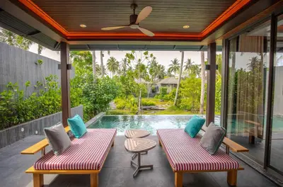a patio with two benches and a swimming pool at Baba Beach Club Phuket Natai Luxury Pool Villa Hotel by Sri panwa in Natai Beach