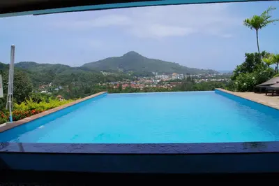 a large swimming pool with a view of a mountain at Baan Chom View Kamala - SHA Plus in Kamala Beach