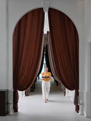 a woman walking down a hallway between two curtains at The Kee Resort & Spa in Patong Beach