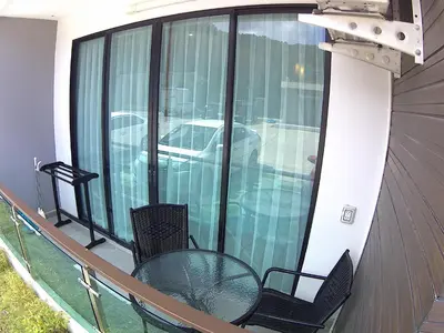 a balcony with a table and chairs and a car outside at Naithon condominium A-103 in Nai Thon Beach