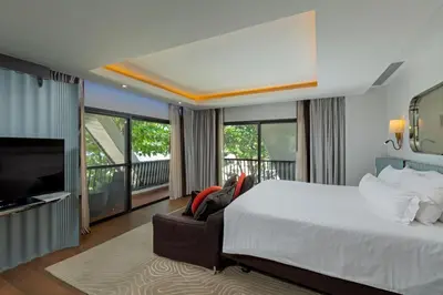 a bedroom with a bed and a couch and a television at The Boathouse Phuket-SHA Plus in Kata Beach