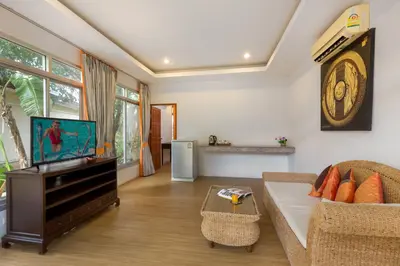 a living room with a couch and a tv at Phuket Sea Resort SHA Extra Plus in Rawai Beach