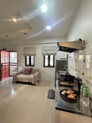 a kitchen with a stove and a living room at The Endless Bangtao Residence CAC 3 in Bang Tao Beach