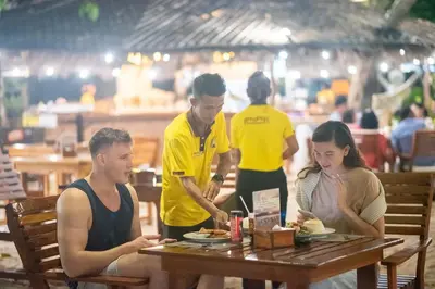 a group of people sitting at a table eating food at Phi Phi The Beach Resort in Phi Phi Don