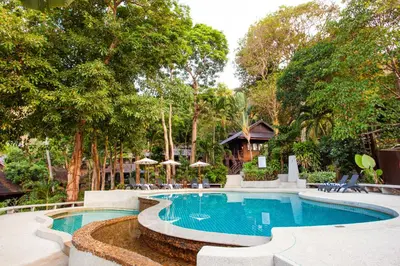 a pool at a resort with trees and umbrellas at Baan Krating Phuket Resort Naiharn-SHA Plus in Nai Harn Beach