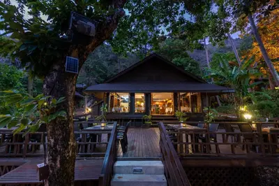 a restaurant with tables and chairs and a tree at Baan Krating Phuket Resort Naiharn-SHA Plus in Nai Harn Beach