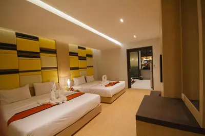 a hotel room with two beds and a desk at Platinum Hotel and Apartments in Patong Beach