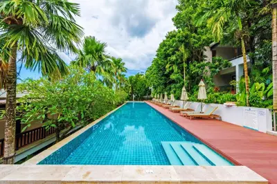 a pool at a hotel with chairs and palm trees at Wyndham Sea Pearl Resort, Phuket in Patong Beach