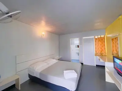 a white bedroom with a bed and a television at Summer Hotel in Phuket Town