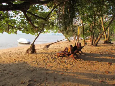 a group of people sitting on benches on a beach at KhaoTong Villa at Melina's in Tha Lane Bay