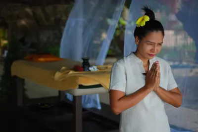 a woman standing in front of a table praying at KhaoTong Villa at Melina's in Tha Lane Bay