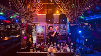a man standing behind a bar with bottles of alcohol at Phi Phi Relax Beach Resort in Phi Phi Don