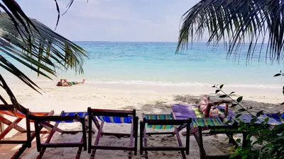 a person sitting in a chair on a beach at Phi Phi Relax Beach Resort in Phi Phi Don