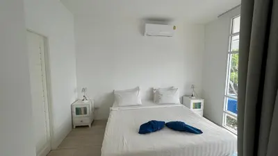a white bedroom with a bed with two blue shoes on it at PP Blue Sky Resort-SHA Plus in Phi Phi Don