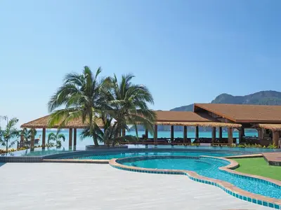 a pool at a resort with palm trees and the ocean at Phi Phi Andaman Beach Resort in Phi Phi Don