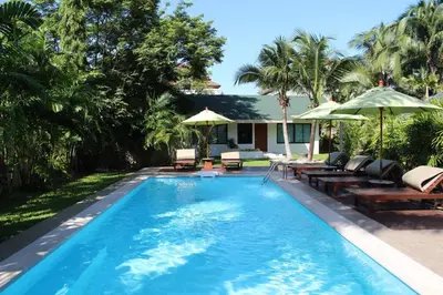 a pool with chairs and umbrellas next to a house at Villa Raeya in Ao Nang Beach