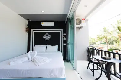 a bedroom with a bed and a table and a balcony at Vacation Time House in Nai Yang Beach