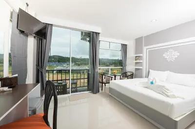 a bedroom with a large bed and a balcony at Vacation Time House in Nai Yang Beach