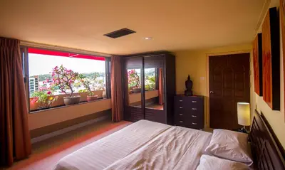 a bedroom with a bed and a large window at Bougainvillea Terrace House in Kata Beach