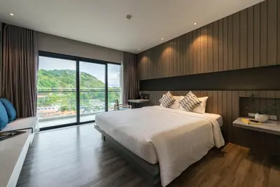 a bedroom with a large bed and a large window at Hotel IKON Phuket - SHA Extra Plus in Karon Beach