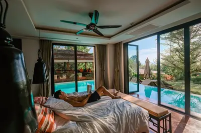 a man laying in bed in a bedroom with a swimming pool at VILLA Chacha VILLA Coco RESORT APOLLONIA in Ko Yao Noi